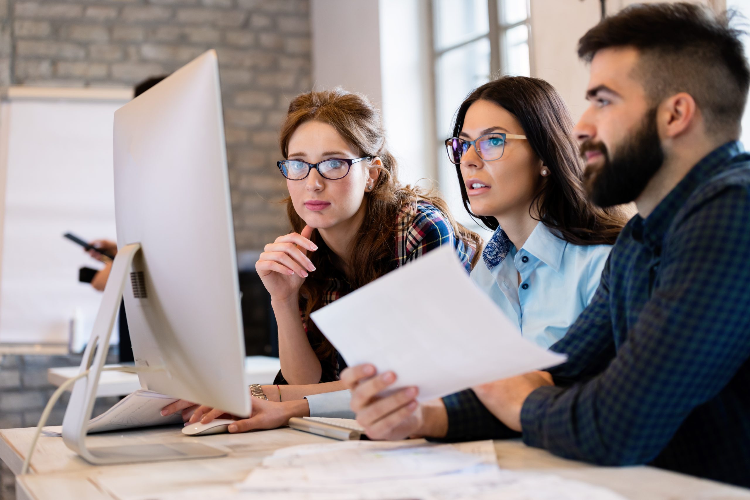 Grupo de pessoas em seu local de trabalho frente ao computador